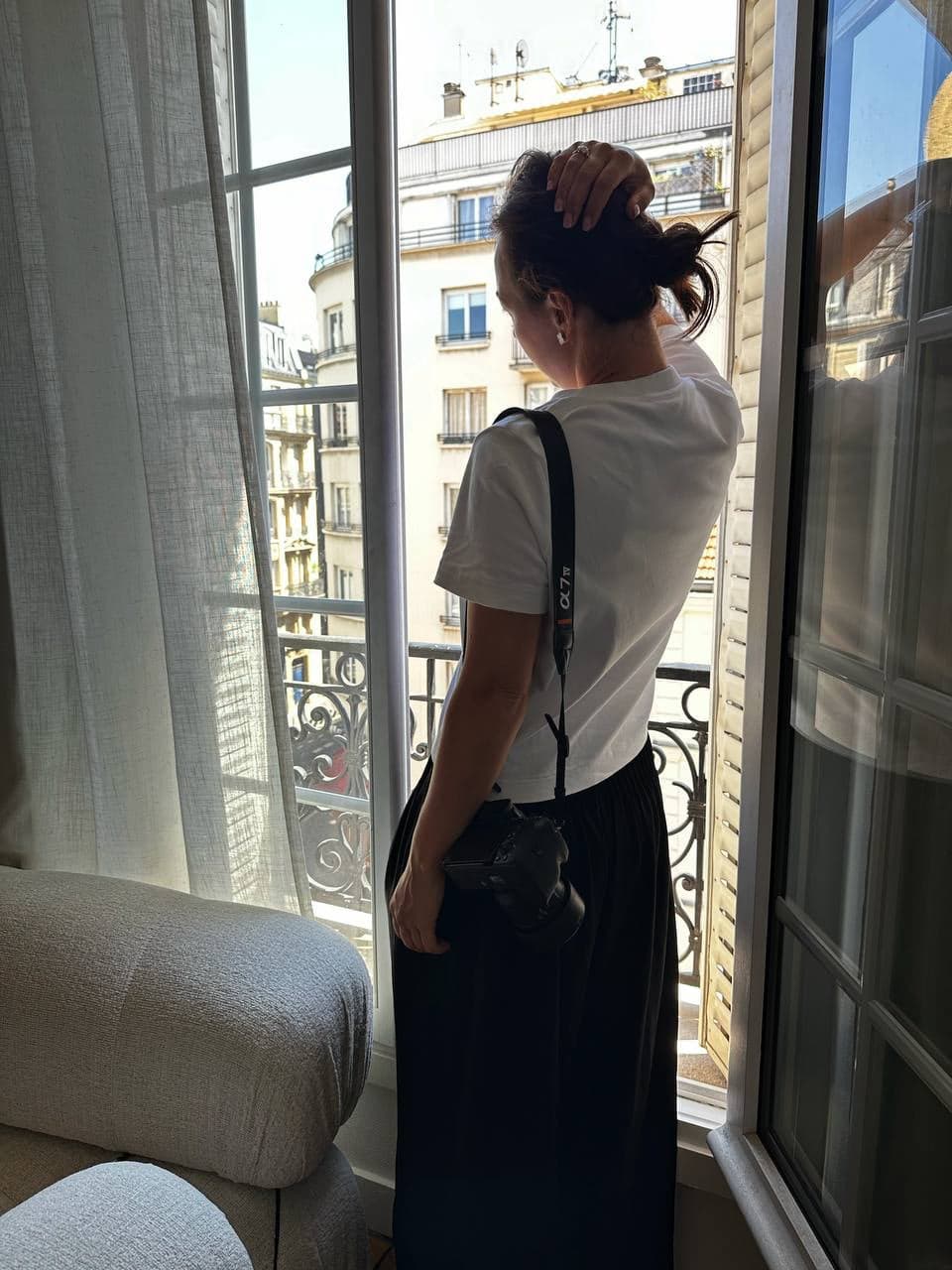 Alina Taran by a window, camera on her shoulder